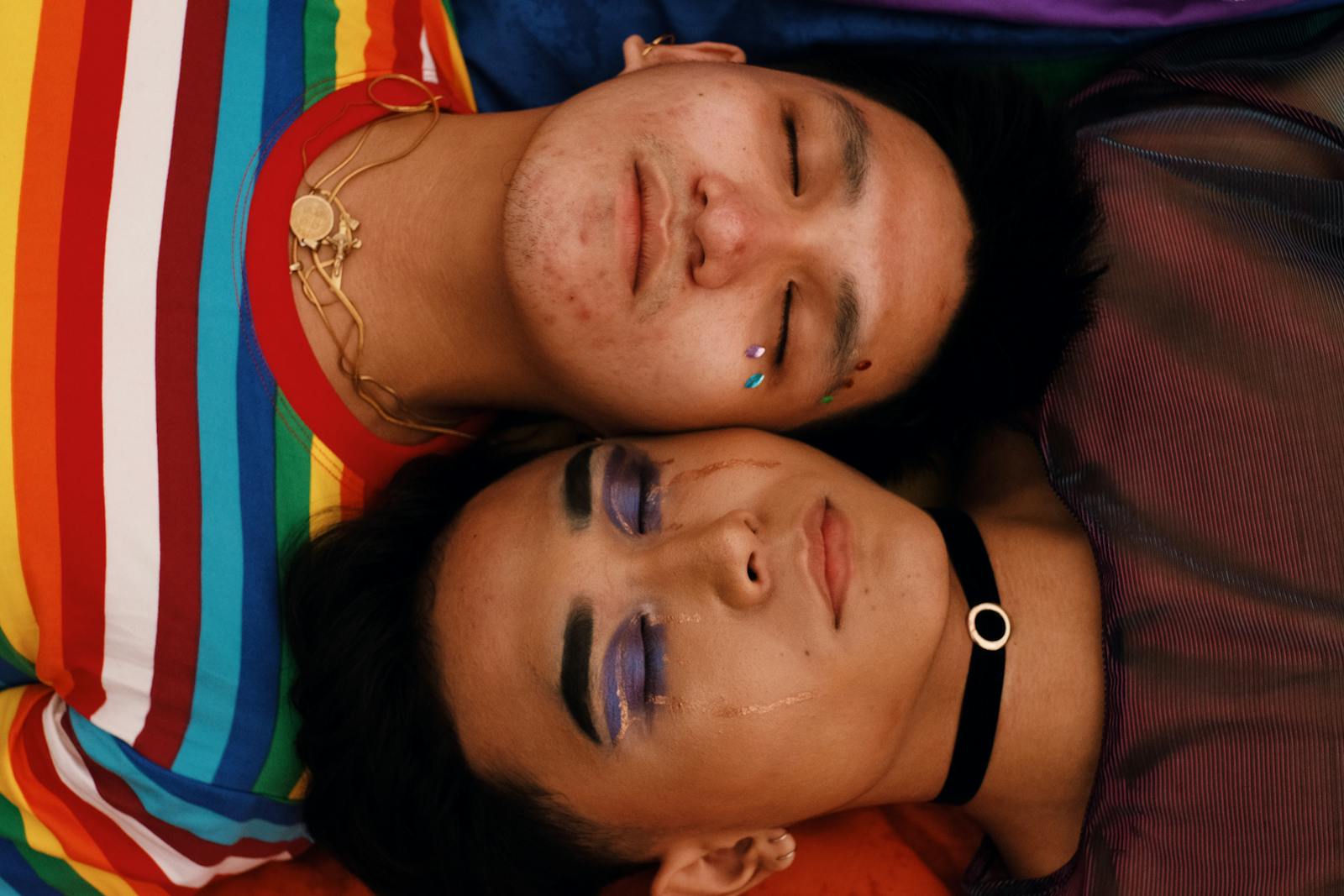 Two people wearing makeup and sequins, lying down next to one another