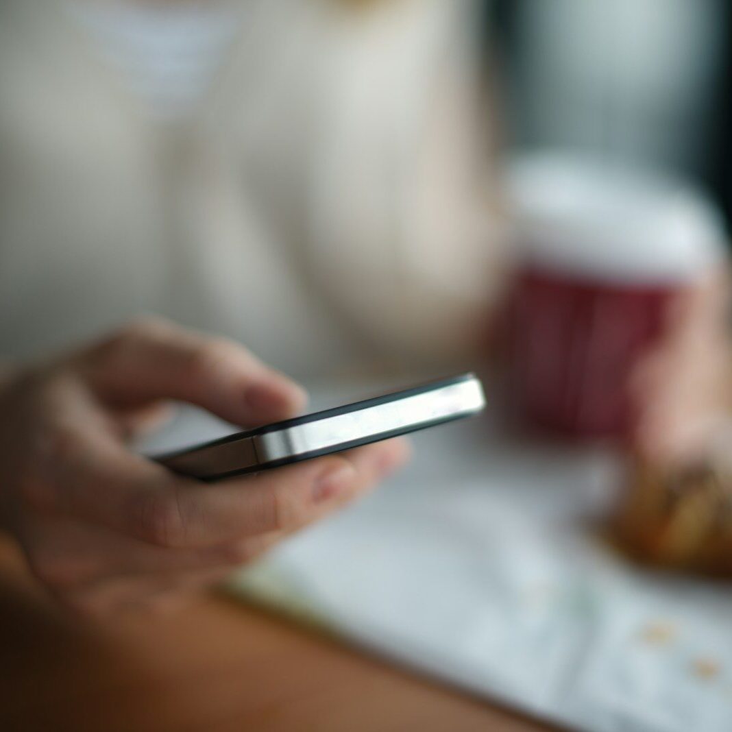 Selective focus photography of person holding gray smartphone phone